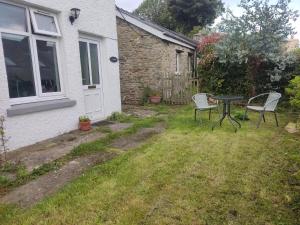 a patio with two chairs and a table in a yard at Garden Room in Cardigan +3 photos