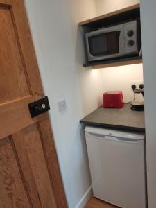 a small kitchen with a microwave and a refrigerator at Garden Room in Cardigan