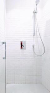 uma casa de banho em azulejos brancos com um chuveiro com um botão vermelho em Jacks Haus em Lugano