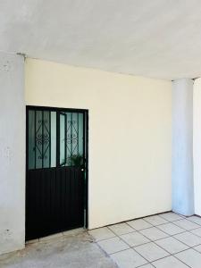 een witte muur met een zwarte deur erop bij Casa Ranitas in Tepic