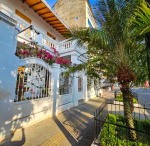 a white building with a palm tree next to a street at La Mercedes Boutique Hostal By MH in Cali