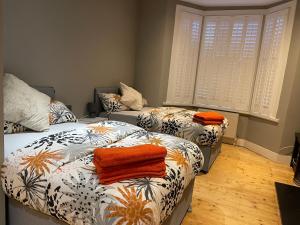 two beds in a room with orange towels on them at Home in Greenwich near the O2 in London