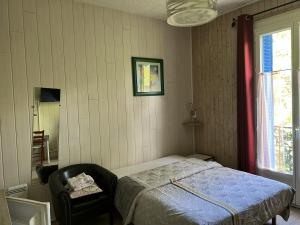 um quarto com uma cama, uma cadeira e uma janela em Studio avec wifi a Neris les Bains em Néris-les-Bains