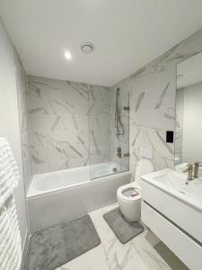 a bathroom with a tub and a toilet and a sink at Apex Lofts Suite - Modern 2 bed with rooftop terrace in Birmingham