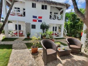 ein weißes Haus mit Stühlen und einem Tisch in der Unterkunft Bayahibe Guest House Hotel in Bayahibe