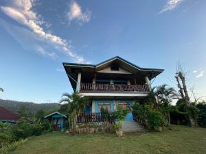 uma casa com uma varanda no topo de um quintal em Santa Claus Hilltop em San Vicente