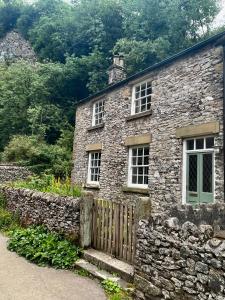 an old stone house with windows and a fence at Torside Holiday Cottage in Castleton