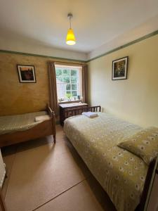 a bedroom with two beds and a desk and a window at Torside Holiday Cottage in Castleton