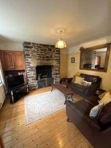 a living room with a couch and a stone fireplace at Torside Holiday Cottage in Castleton
