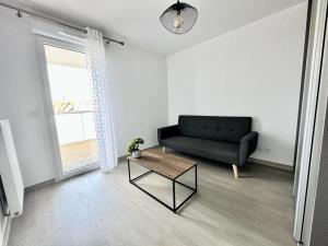 a living room with a black couch and a table at La Frontalière in Ambilly