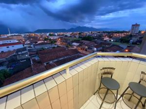 two chairs on a balcony with a view of a city at Pé na Areia Praia do Caiçara in Solemar