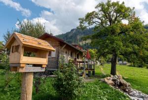 a wooden bird house on a wooden pole in front of a house at Tinyhouse Momente Chalet als Rückzugsort für Naturliebhaber im Oberallgäu in Wertach