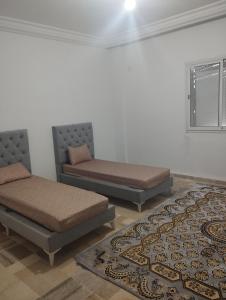 2 camas en una habitación con alfombra en Jad tunis, en Túnez