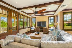 ein Wohnzimmer mit einem Deckenventilator und einem TV in der Unterkunft Charming Coastal Cottage in Kukuiula- Alekona Kauai in Koloa