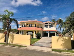 une grande maison avec des palmiers en face de celle-ci dans l'établissement Caribbean Sunshine Villa, à Aguadilla