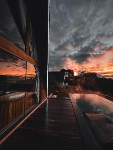 a building with a deck with a sunset in the background at Chalés Laguna Alto Viçosa in Venda Nova do Imigrante