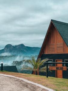 un bâtiment avec un panneau indiquant le milaq à côté d'une montagne dans l'établissement Chalés Laguna Alto Viçosa, à Venda Nova do Imigrante