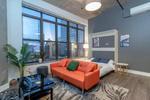 a living room with an orange couch and a bed at Slumber Stay - McCormick in Chicago