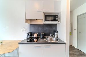 eine Küche mit einer Spüle und einer Mikrowelle in der Unterkunft Studio proche tête d'Or 2 personnes Villeurbanne in Villeurbanne