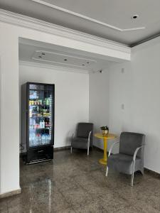カンピーナスにあるLize Prime Hotelの椅子2脚、冷蔵庫、テーブルが備わる客室です。