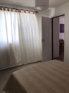a bedroom with a bed and a window with white curtains at Lo de tungo in Paraná