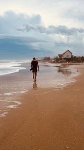 a man walking on the beach with a surfboard at Recodo de mar in Aguas Dulces