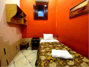 een kleine kamer met een bed met een oranje muur bij Golden Hotel Cairo in Caïro