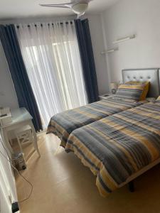 een slaapkamer met 2 bedden en een raam met gordijnen bij Casa Paradise, Apartment in Torre-Pacheco