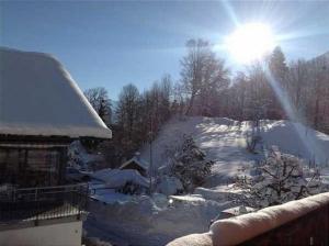 a snow covered yard with a house and the sun at Haus Glyssen - b48482 in Kienholz