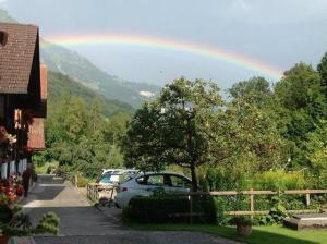 a rainbow in the sky over a parking lot with cars at Haus Glyssen - b48482 in Kienholz