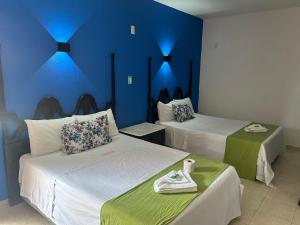 Habitación con 2 camas y pared azul en Hotel Capri Playa a una calle de la Playa Regatas en Veracruz