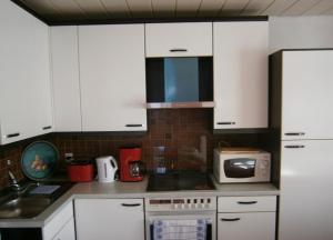 a kitchen with white cabinets and a microwave at Gemütliche Wohnung in Liggersdorf mit Grill, Garten und Terrasse - b48489 in Hohenfels