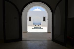 an archway leading into a room with a blue chair at Maison Rachid Djerba in El Guecheïne