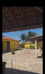 a patio with two tables and a yellow building at Chácara in Estância
