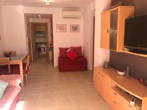 salon z czerwoną kanapą i telewizorem w obiekcie Apartamento junto al mar Los Marineros con acceso independiente por terraza w mieście Puzol