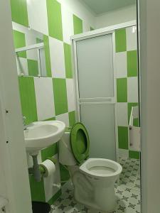 a green and white bathroom with a toilet and sink at HOTEL EL EMPERADOR in Doradal