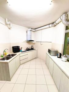 a kitchen with white cabinets and a sink and a window at TuR15 PisaStadium 9pax 4rooms PrivateHouse in Bayan Lepas