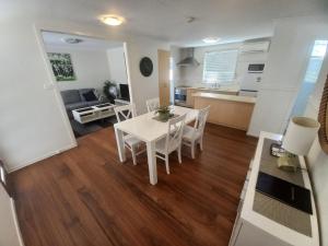 cocina y sala de estar con mesa blanca y sillas en Oceana Holiday Units, en Coffs Harbour