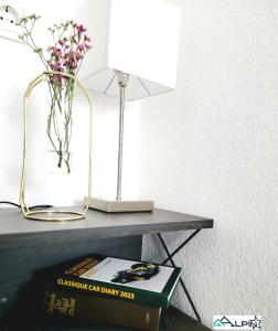 a table with a lamp a book and a vase of flowers at Ferienwohnung Alpinstar - inklusive Oberstaufen Plus in Oberstaufen