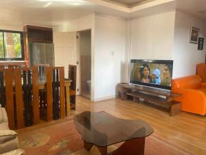 a living room with a large flat screen tv at Country Homes Sheridan Drive Camp John Hay Lot 16 in Baguio