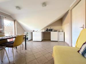 een woonkamer met een tafel en een keuken bij Rozsé Apartman-tetőtér in Budaörs