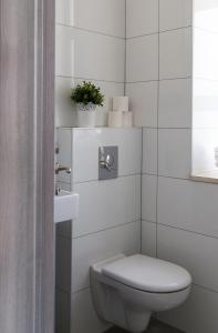 een witte badkamer met een toilet en een plant bij Ben Hillel Boutique Hotel in Jeruzalem