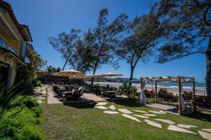 un patio con mesas y sombrillas en la playa en Pousada dos Gravatás, en Búzios