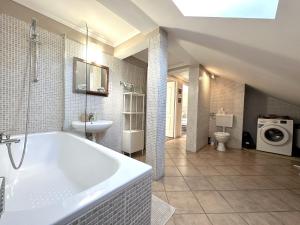La salle de bains est pourvue d'une baignoire, d'un lavabo et d'un lave-linge. dans l'établissement Rozsé Apartman-tetőtér, à Budaörs