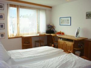 a bedroom with a bed and a desk and a window at Apparthotel Pöstli Nr 307 - b48499 in Maloja