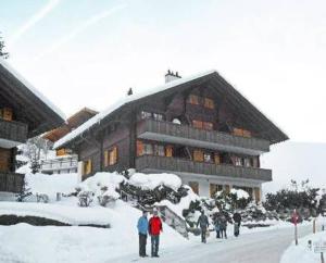 personas de pie en la nieve frente a un edificio en Chalet Kiefer - b48527, en Grindelwald