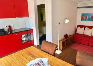 cocina con armarios rojos, mesa y sofá en Pilgerwohnung - b48531, en Wald