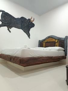 a statue of a bull on a wall next to a bed at HOTEL EL EMPERADOR in Doradal