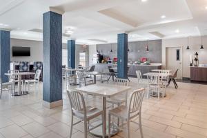 a dining room with tables and chairs and a kitchen at Best Western Plus Stephenville Inn in Stephenville