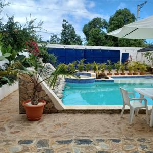 een zwembad met een tafel, stoelen en planten bij Tropical Doña Mayra apartahotel in Las Terrenas